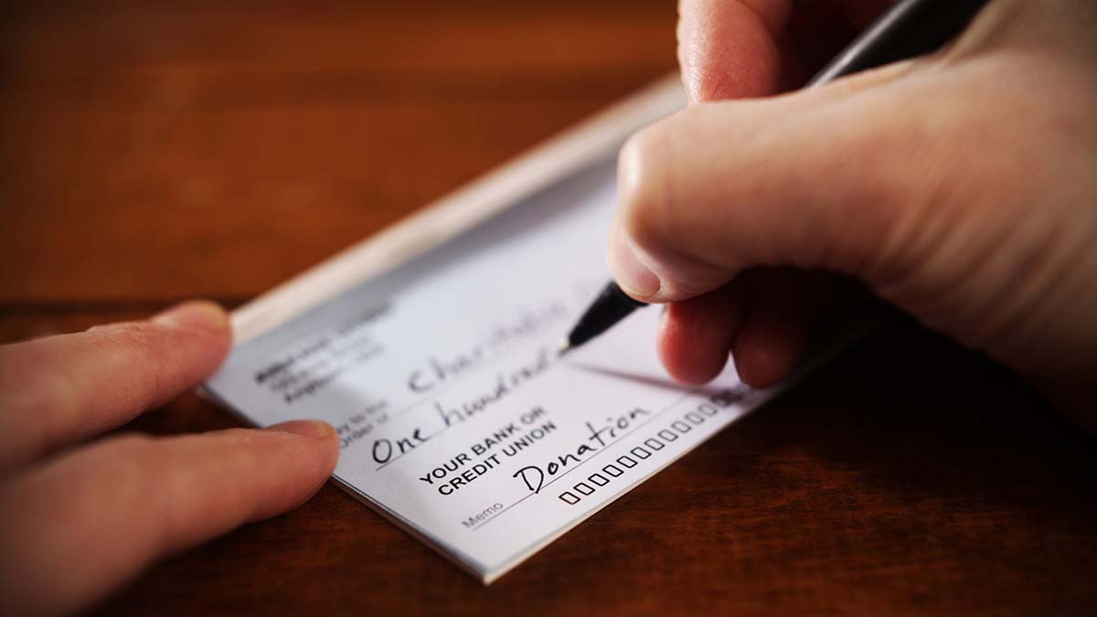Corporate Foundation or Organizational Support | Close up View of Hand Writing A Donation Check