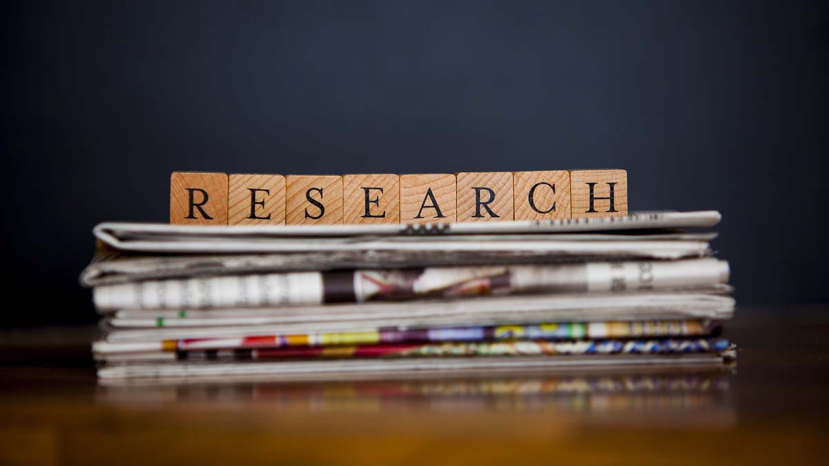 Research Strategy | Stacks of newspapers and articles written with wooden blocks